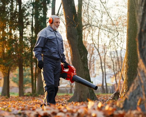Man working with leaf blower to clean up alleys. Man working with leaf blower to clean up alleys.