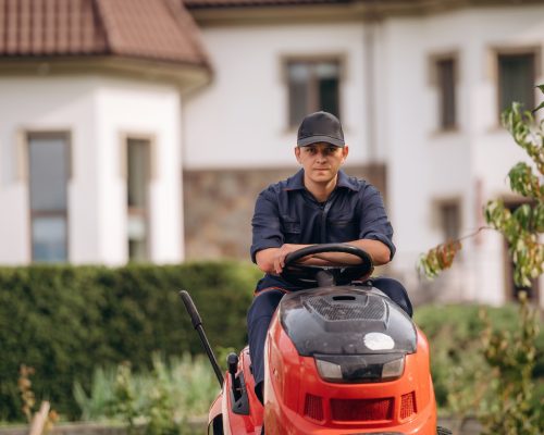 Sitting on the lawn mover. Professional gardener is on the lawn Sitting on the lawn mover. Professional gardener is on the lawn